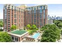 Luxury high-rise apartment building featuring a rooftop pool, lush landscaping, and views of the city skyline at 1820 Peachtree Nw St # 804, Atlanta, GA 30309