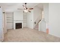 Bright living room boasts a fireplace, built-in shelving, neutral carpet, and staircase to upper level at 1926 Cheatham Woods Sw Dr, Marietta, GA 30008