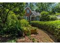 Brick home surrounded by lush landscaping, including mature trees, bushes, and potted plants at 401 Emory Ne Dr, Atlanta, GA 30307
