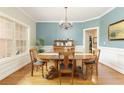 Classic dining room features elegant wainscoting, hardwood floors and a beautiful chandelier at 6765 Creek View Ln, Cumming, GA 30041
