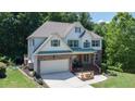 Inviting two-story home with a large front yard, attached garage, stone and brick accents, and green trim details at 6765 Creek View Ln, Cumming, GA 30041