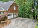 Long driveway leading to a two-car garage with mature trees and a basketball hoop in the background at 992 Marbury Sw Ct, Marietta, GA 30064