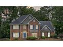 Charming brick two-story home with a blue front door, a manicured lawn, mature trees, and dark shutters at 992 Marbury Sw Ct, Marietta, GA 30064