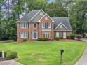 Well-maintained lawn and landscaping frame this two-story brick home with a blue front door and dark shutters at 992 Marbury Sw Ct, Marietta, GA 30064