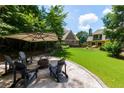Backyard fire pit with Adirondack chairs on a stone patio surrounded by lush greenery at 650 Chestatee Creek Nw Dr, Acworth, GA 30101
