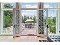 Expansive patio view through large french doors, showcasing an outdoor dining and lounging area, surrounded by lush landscaping at 100 5Th St, Fayetteville, GA 30214