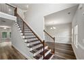 Elegant staircase with wood and iron railings, leading to an open floor plan with hardwood floors and modern lighting at 176 Windy Cir, Mcdonough, GA 30253
