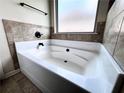 Bathroom showcasing a clean, white tub with tiled accents and natural light from the window at 958 Nevis Way, Mcdonough, GA 30253