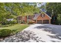 Elegant brick home with large driveway, mature trees, manicured lawn and three-car garage at 1835 Redbourne Dr, Atlanta, GA 30350