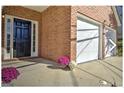 Inviting front entrance with a black door, sidelights, and colorful potted flowers by the garage at 1399 Cutters Mill Dr, Lithonia, GA 30058