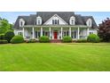 Charming home boasts a beautiful wrap-around porch, red front door, and manicured front lawn at 1415 N Flat Rock Rd, Douglasville, GA 30134