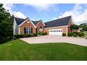 Traditional brick home featuring a two-car garage, manicured lawn, and lush landscaping on a sunny day at 7090 Valley Landing Ct, Cumming, GA 30041