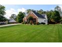 Expansive, well-maintained lawn surrounds the charming home, complemented by mature trees in the background at 7090 Valley Landing Ct, Cumming, GA 30041