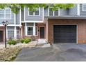 Close-up of a well-maintained townhome featuring brick accents, garage, and landscaped front yard at 2680 Pine Tree Ne Rd # 2, Atlanta, GA 30324