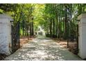 Gated driveway leading to a stately home, surrounded by mature trees and lush landscaping at 1016 Old Powers Ferry Rd, Atlanta, GA 30327