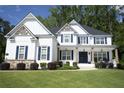 Inviting two-story home boasts a manicured lawn, tasteful landscaping, and a classic white facade with dark blue accents at 1895 Henley Way, Alpharetta, GA 30009