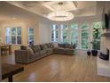Spacious living room with hardwood floors, coffered ceiling, large windows, and a comfortable sectional sofa at 1895 Henley Way, Alpharetta, GA 30009