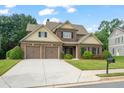Charming two-story home with a well-manicured lawn, brick facade, and a two-car garage on a sunny day at 452 Rockford Pass, Marietta, GA 30064