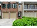 Traditional townhome featuring a brick facade, two-car garage, and manicured shrubbery at 2515 Gadsen Walk, Duluth, GA 30097