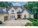 Elegant home with a well-manicured lawn, mature trees, and a driveway leading to an attached garage at 2885 Coles Way, Atlanta, GA 30350