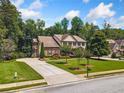 Beautiful home with a well-manicured lawn, complemented by mature trees and a long driveway at 1344 Hamilton Creek Nw Dr, Kennesaw, GA 30152