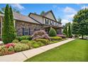 Inviting two-story home with a stone facade, lush landscaping, and a well-maintained lawn at 1344 Hamilton Creek Nw Dr, Kennesaw, GA 30152