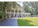 Spacious front exterior showcases the home's lawn, mature trees, and classic column design at 575 Valley Hall Dr, Sandy Springs, GA 30350