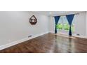 Bright living room with hardwood floors, large window with blue curtains, and decorative shelving at 2142 Troutdale Dr, Decatur, GA 30032