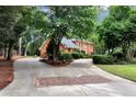 Long driveway leading to a brick home surrounded by mature landscaping and trees at 1320 Northcliff Trce, Roswell, GA 30076