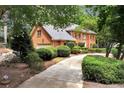 Brick home featuring a three car garage and a driveway lined with manicured bushes and mature trees at 1320 Northcliff Trce, Roswell, GA 30076