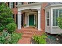 Close-up of the front entrance with brick steps, a green door, and decorative plants at 1775 Porterton Way, Cumming, GA 30041
