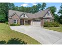 Beautiful single-Gathering home with a brick exterior, lush green lawn, and an expansive concrete driveway leading to a two-car garage at 902 Edgewater Dr, Loganville, GA 30052