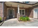 Close-up of a brick home's entryway with stone accents, a gray front door, and manicured landscaping at 902 Edgewater Dr, Loganville, GA 30052
