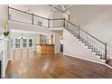 Open-concept living room featuring hardwood floors, soaring ceilings, staircase, and dining area with a bar counter at 1605 Spinnaker Drive, Alpharetta, GA 30005
