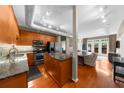 Open-concept kitchen with wood cabinets, stainless steel appliances, granite countertops, and hardwood floors at 5300 Peachtree Rd # 1608, Chamblee, GA 30341