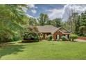 Beautiful brick home featuring a lush green lawn, mature trees, and lovely landscaping at 1041 Flat Rock Rd, Covington, GA 30014