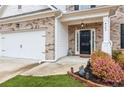 View of front door, 2 car garage, and flower garden of a traditional home with brick and white trim at 4365 Sunflower Cir, Cumming, GA 30040