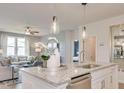 Open-concept kitchen featuring a kitchen island, modern pendants, sink, and view into the adjacent living area at 404 Satilla Ct, Locust Grove, GA 30248