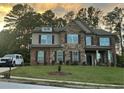 Charming two-story home with brick and stone exterior, dark shutters, and well-manicured lawn under a colorful sky at 2304 Northglenn Ct, Conyers, GA 30013