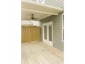 A view of the back porch, showing wood flooring, outdoor fan, and french doors to enter the property at 559 Fundao Ln # 21, Lawrenceville, GA 30046
