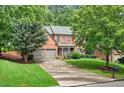 Traditional brick home featuring a two-car garage and a beautifully landscaped front yard at 1065 Bookhout Drive Dr, Cumming, GA 30041