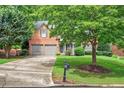Inviting two-story brick home with a lush green lawn and mature trees at 1065 Bookhout Drive Dr, Cumming, GA 30041