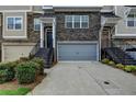Townhome with a gray garage door, stone accents, landscaped bushes, and stairs leading to the front door at 2719 Hedgeway Cir, Kennesaw, GA 30144