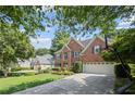 Brick home featuring a two-car garage, a driveway with basketball hoop, and manicured landscaping at 3675 Ridgeway Ter, Suwanee, GA 30024