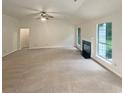 Open living room with a fireplace, large windows, and neutral decor at 46 Timber Walk Dr, Sharpsburg, GA 30277
