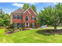 Stately brick home featuring lush green lawn, mature shade trees, and manicured landscaping at 1219 Hadaway Ct, Lawrenceville, GA 30043
