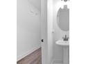 Neat powder room featuring a pedestal sink, oval mirror, and clean white walls at 1958 Dillon Dr, Lithonia, GA 30058