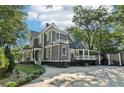 A gray two-story house featuring a covered porch and a large driveway surrounded by green landscaping at 207 E Hightower E Trl, Social Circle, GA 30025