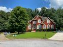 Inviting two-story brick home with mature trees, lush lawn, and a circular driveway at 3008 Sunrise Ct, Conyers, GA 30094
