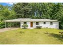 Charming white home featuring a covered carport and a well-maintained front yard, surrounded by lush greenery at 3055 Henderson Mill Rd, Atlanta, GA 30341